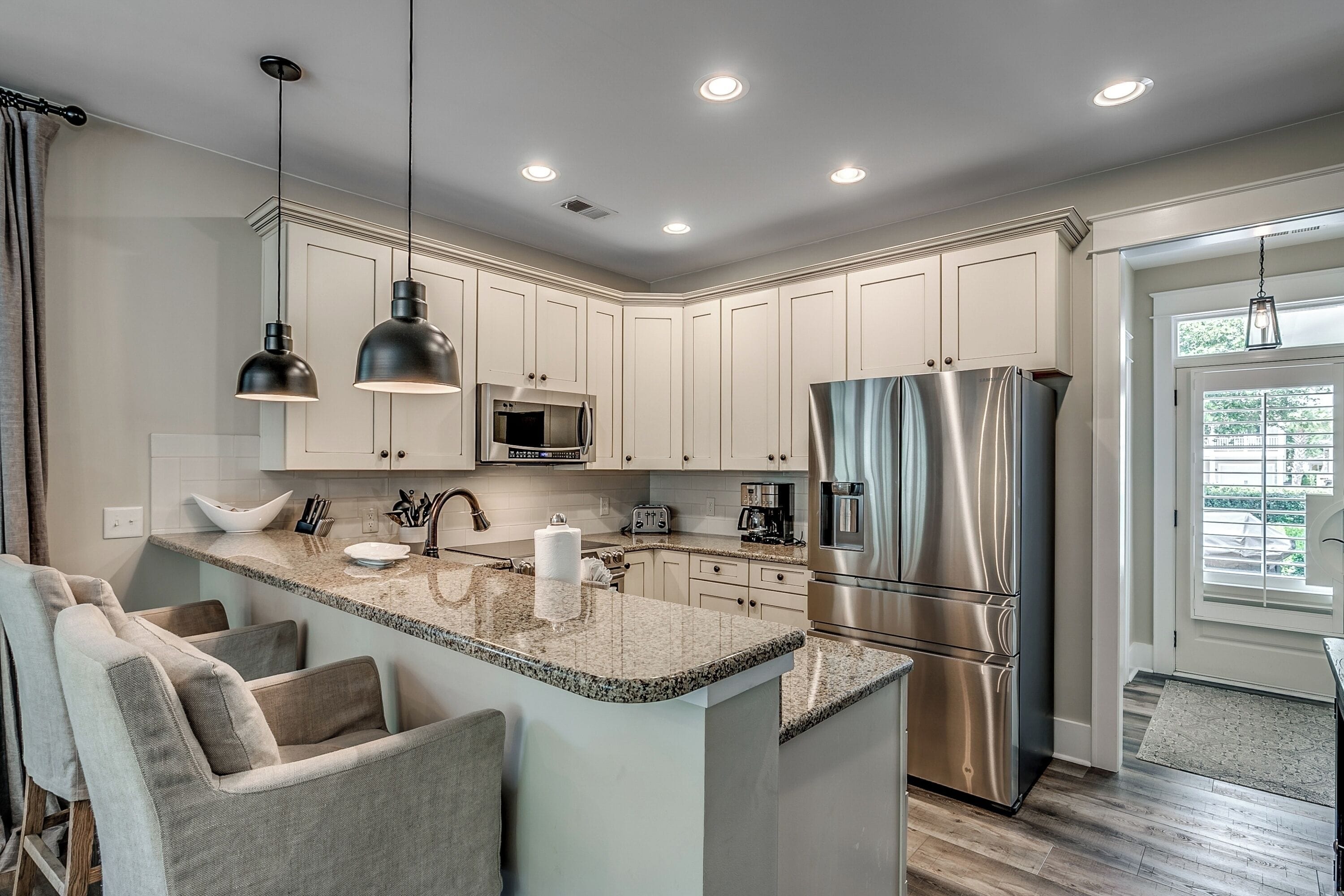 A modern kitchen with white cabinets, stainless steel appliances, and a granite island.
