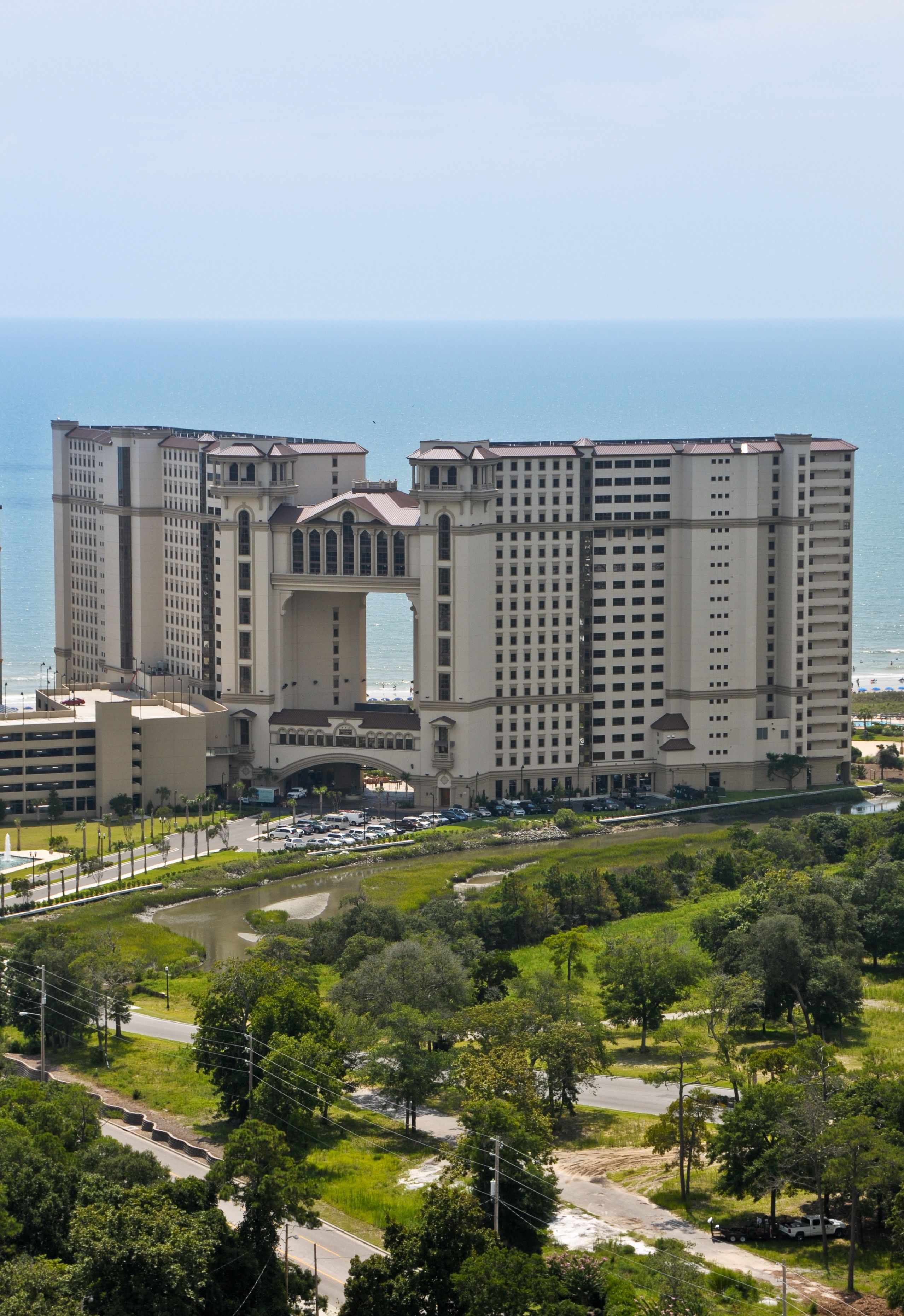 Un grand hôtel doté d’une arche centrale, de plusieurs étages et offrant une vue sur l’océan.