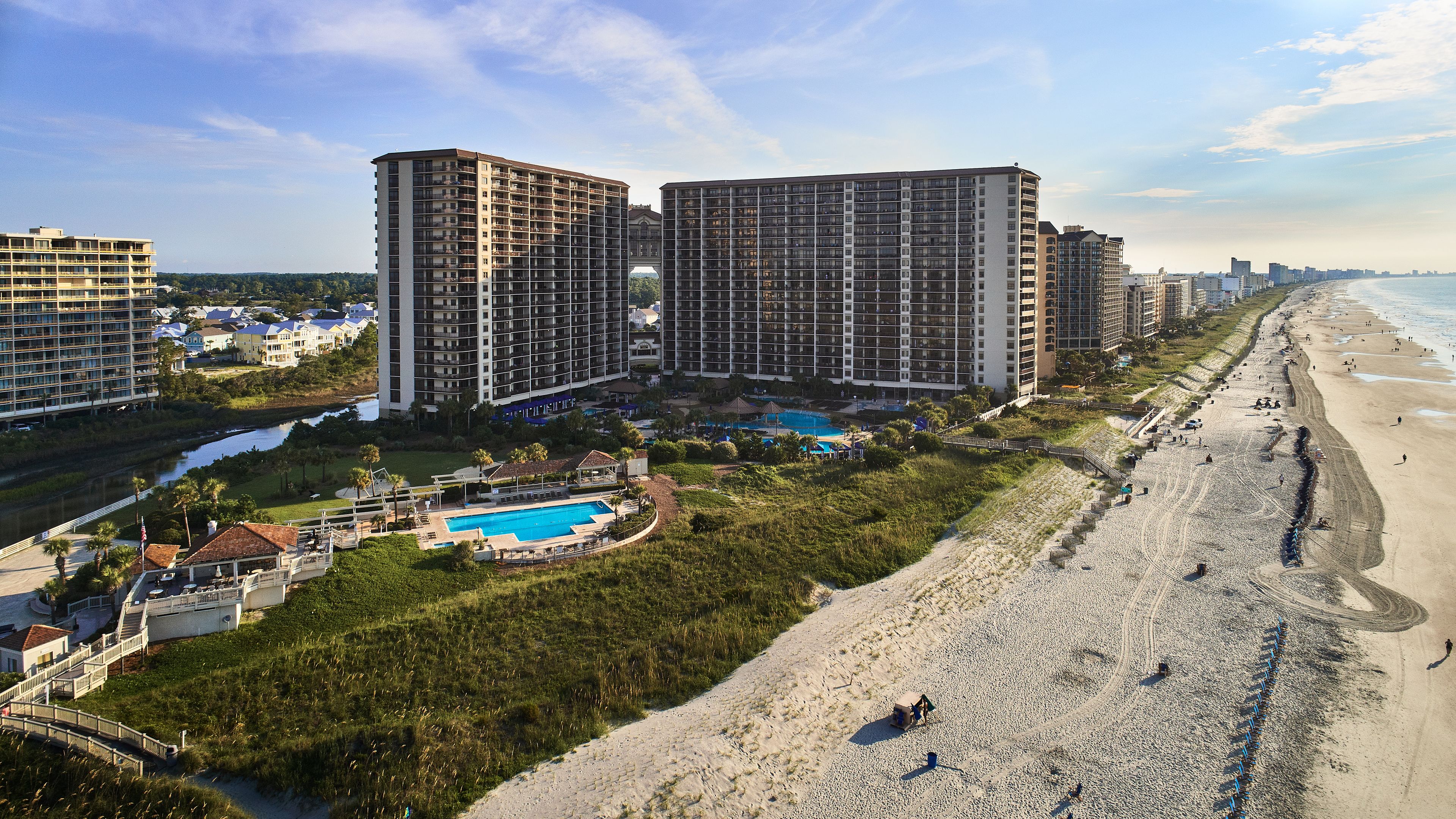 Un hôtel de grande hauteur, doté de nombreux étages, d’une piscine et situé à proximité d’une plage.