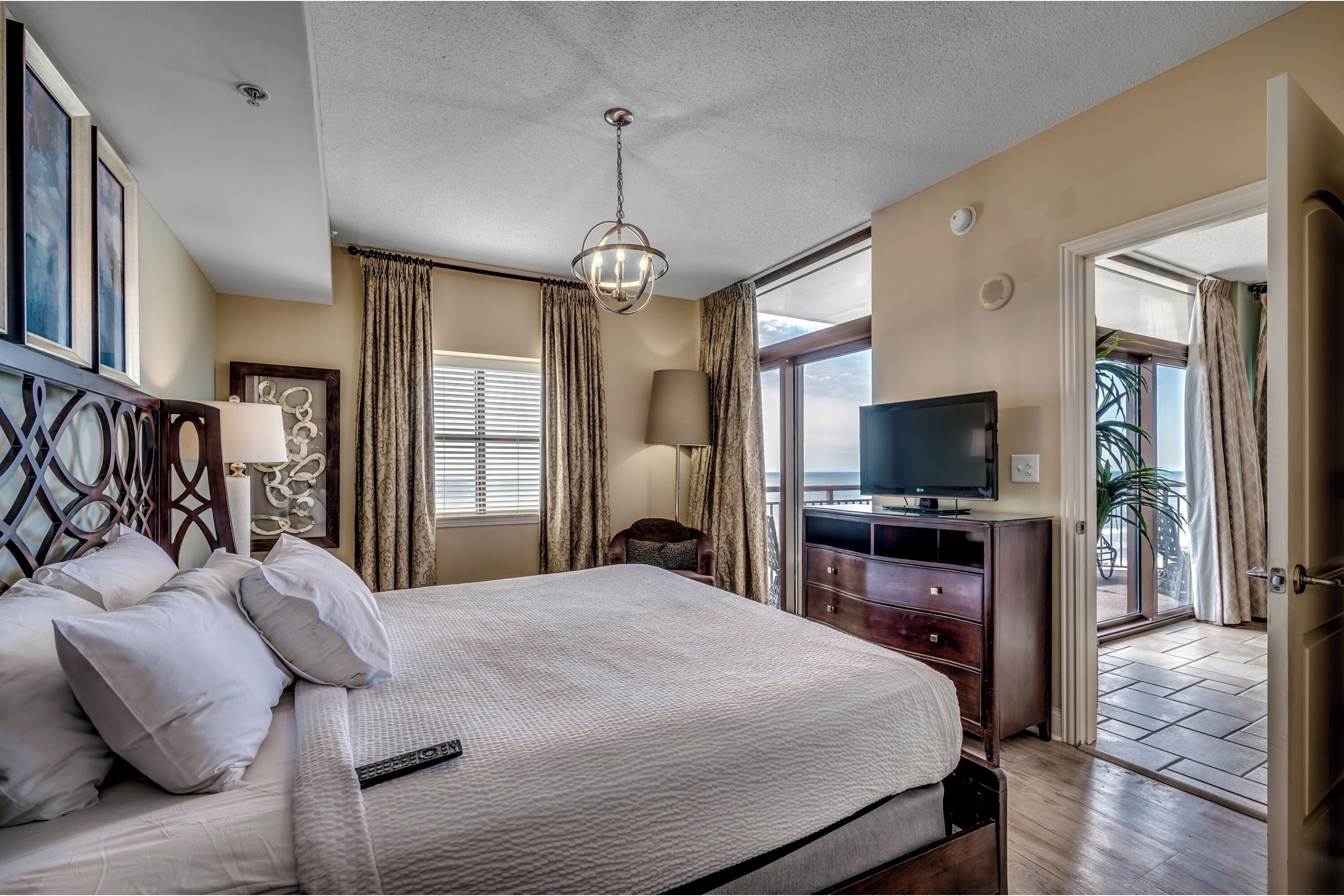 A hotel room with a large bed, a television, a desk, and a view of the outdoors.