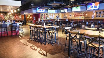 Un restaurant doté de nombreuses tables et chaises, d’un bar et d’un mur sur lequel est affiché un panneau indiquant « Billard ».