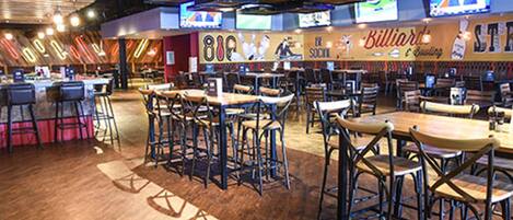 A restaurant with multiple tables and chairs, a bar area, and a wall with a sign that reads "Billiards."