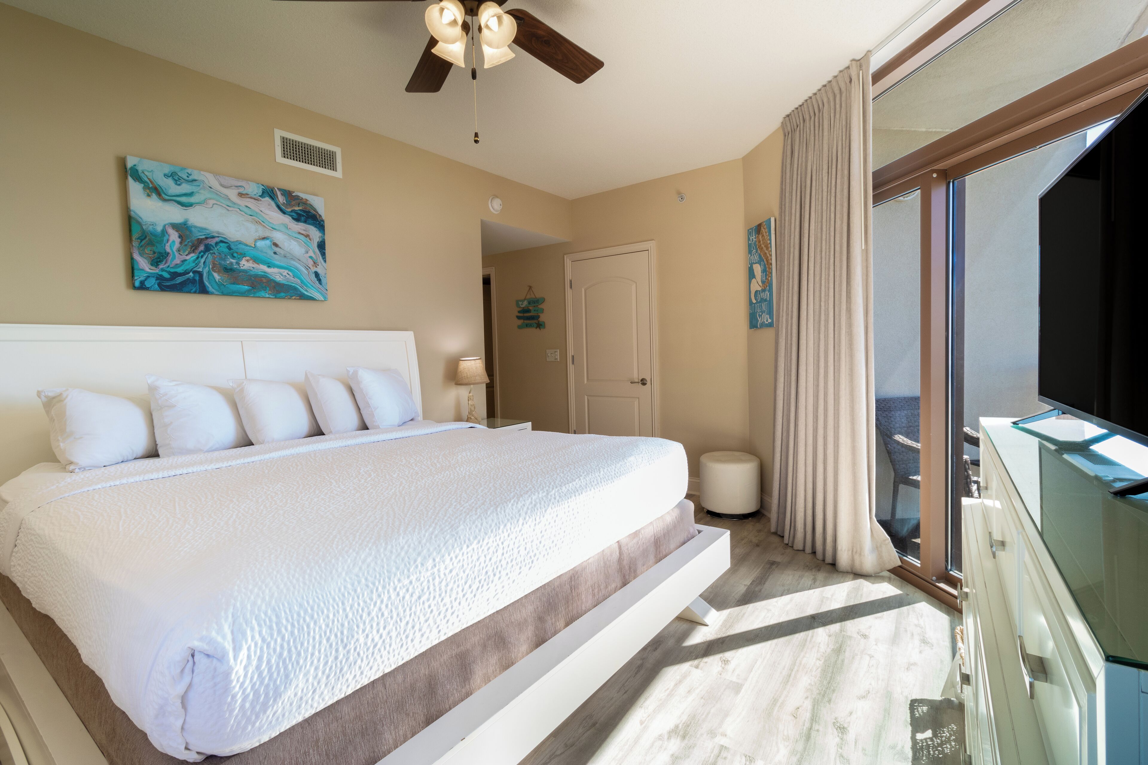 A spacious bedroom with a large bed, a ceiling fan, and a view of the outdoors.