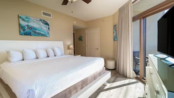 A spacious bedroom with a large bed, a ceiling fan, and a view of the outdoors.