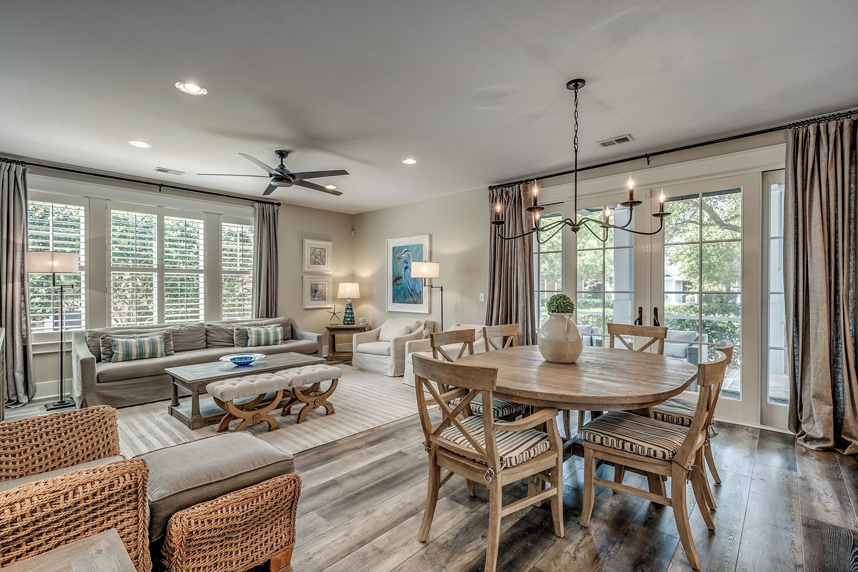 A spacious living room with a large sofa, a dining table with chairs, and a ceiling fan.