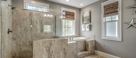 A bathroom with a glass-enclosed shower, a large vanity with a sink, and a mirror.