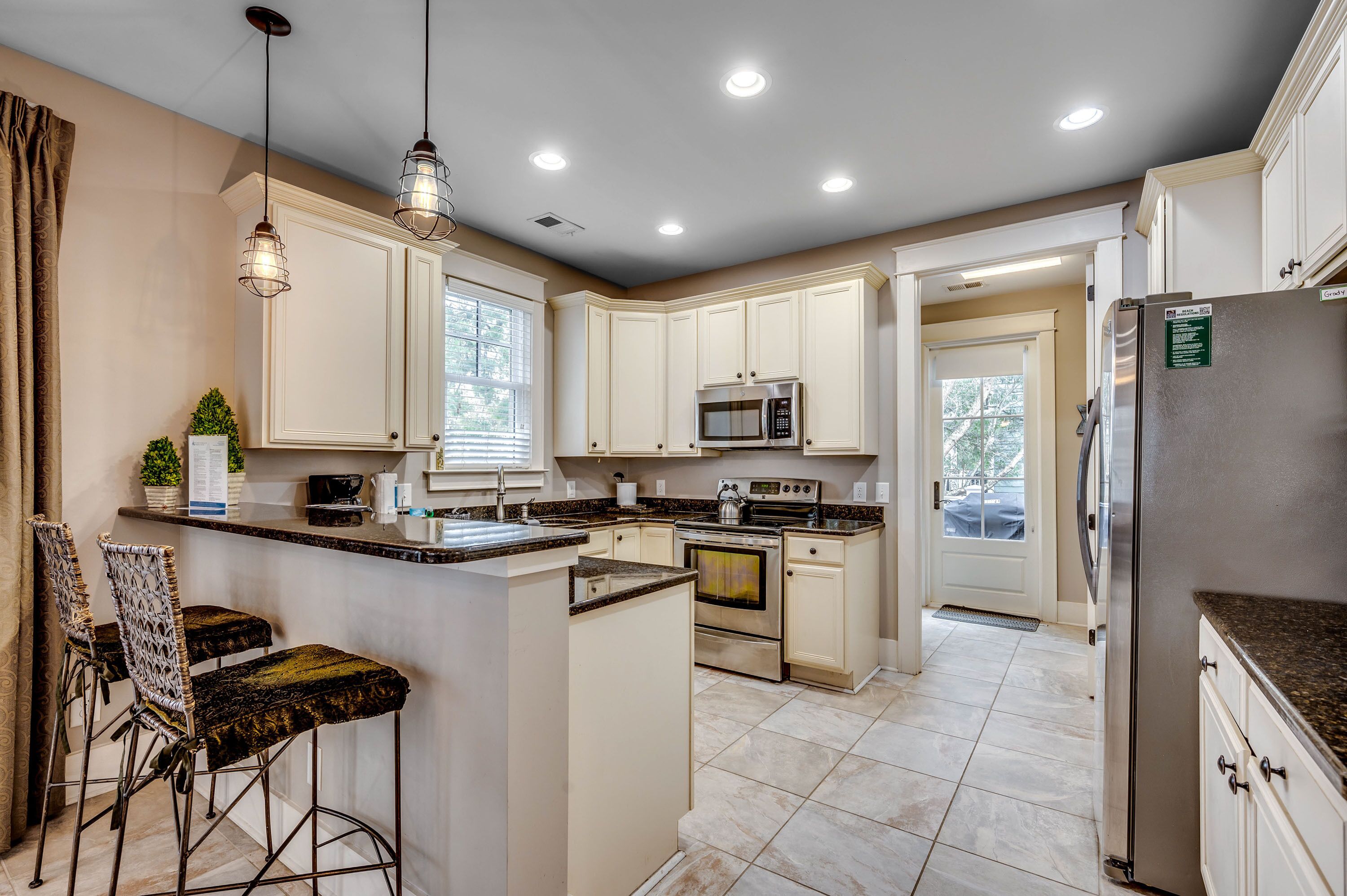 Eine moderne Küche mit weißen Schränken, Edelstahlgeräten und einer zentralen Kochinsel mit Barhocker.