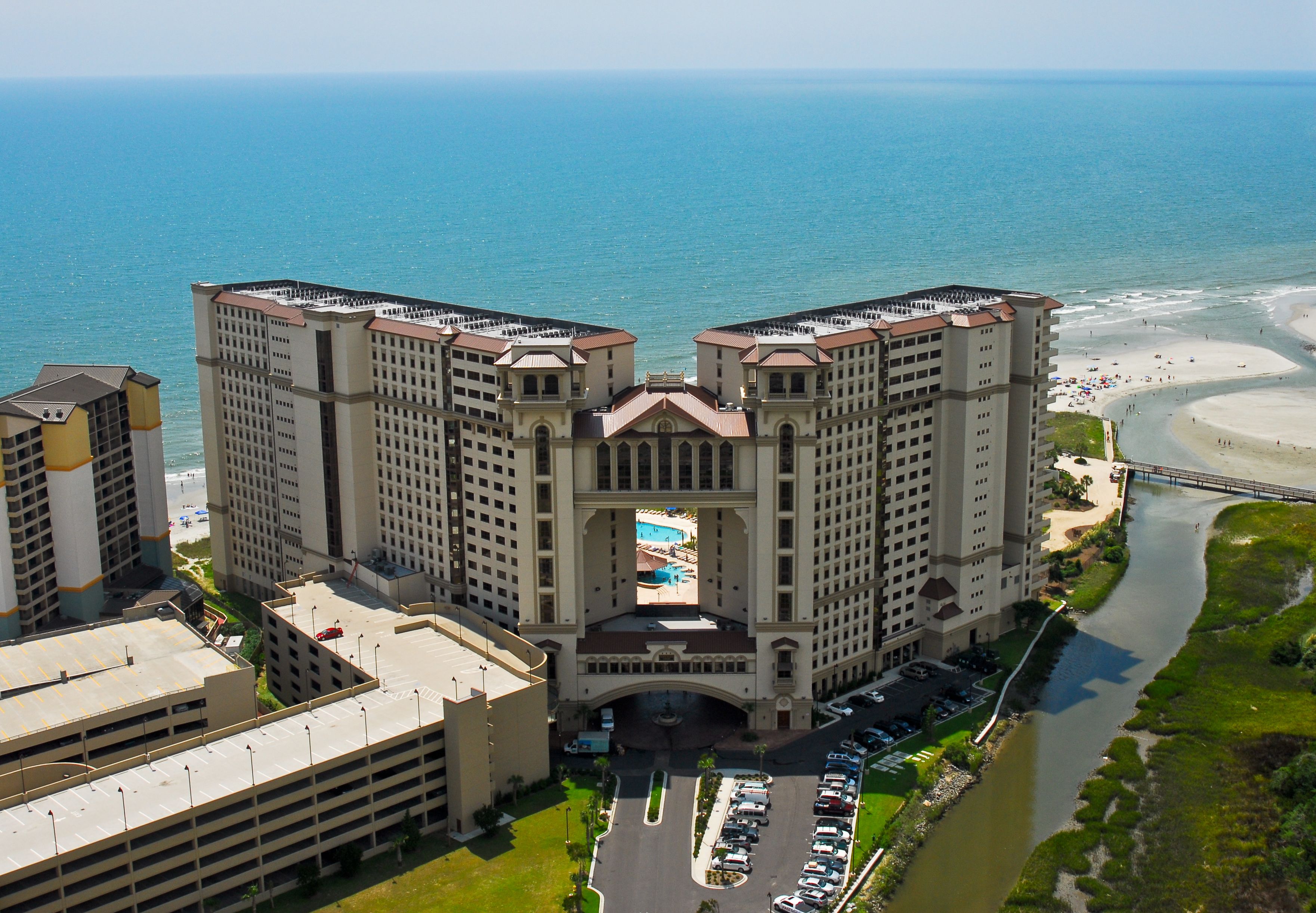 A high-rise hotel with a central courtyard, multiple parking levels, and a view of the beach and ocean.