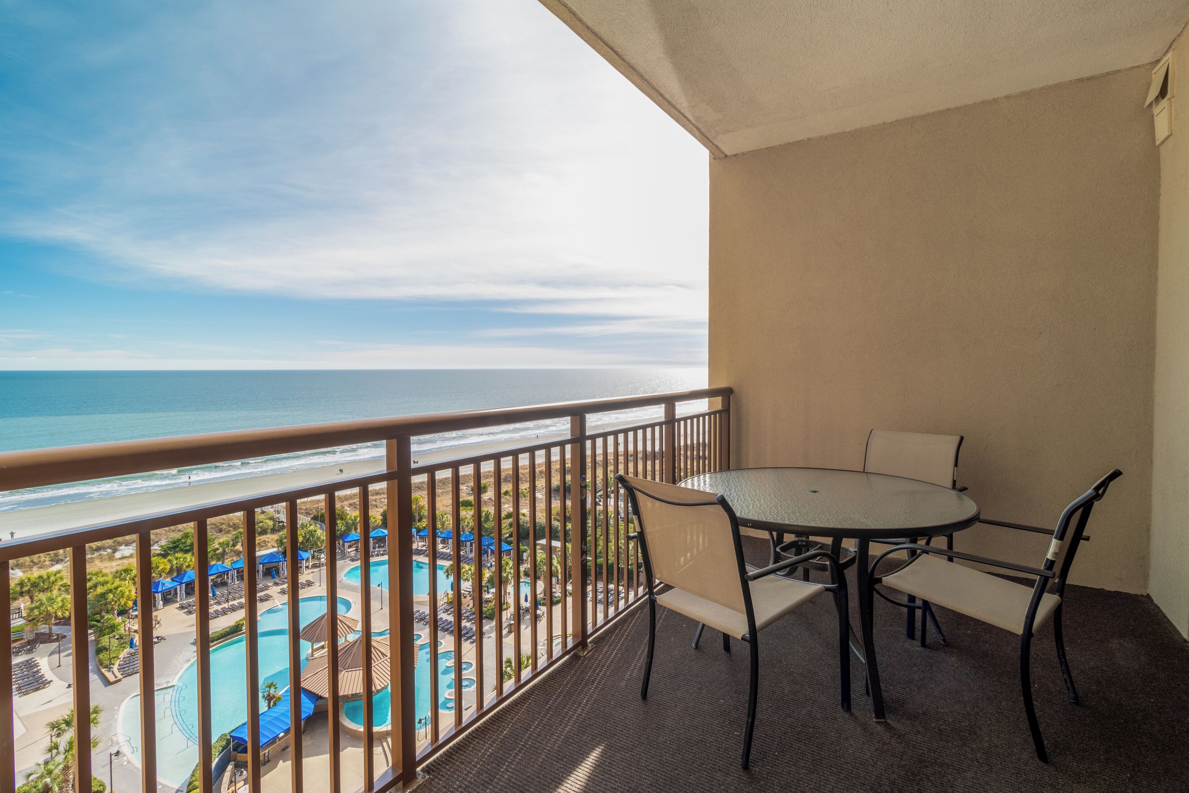 A balcony with a view of the ocean and a pool area.