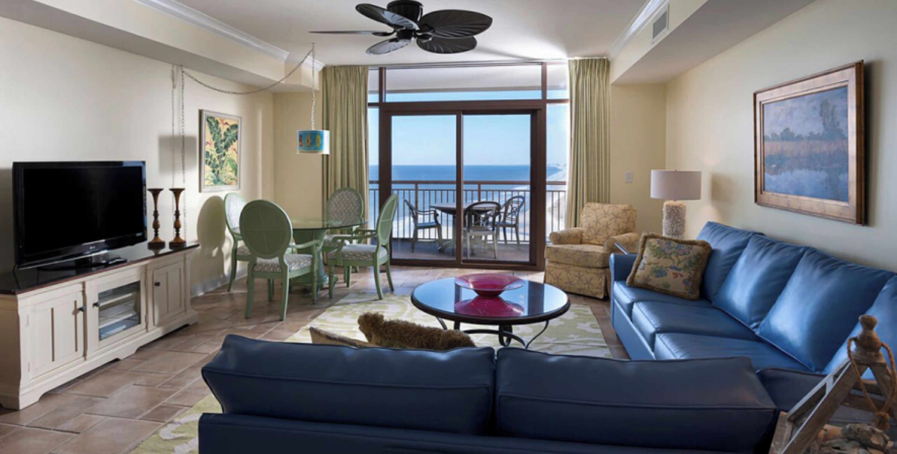 Ein Hotelzimmer mit Balkon, Fernseher, Sofa und Essbereich.