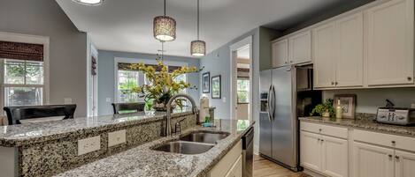 A kitchen with granite countertops, stainless steel appliances, and white cabinetry.