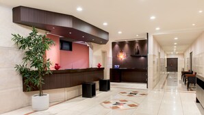 Zona de recepción de un hotel de diseño moderno, con mostrador de recepción, una planta en maceta y un diseño decorativo en el suelo.