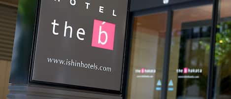 A hotel sign with the name "HOTEL the b" and the website "www.ishinhotels.com".