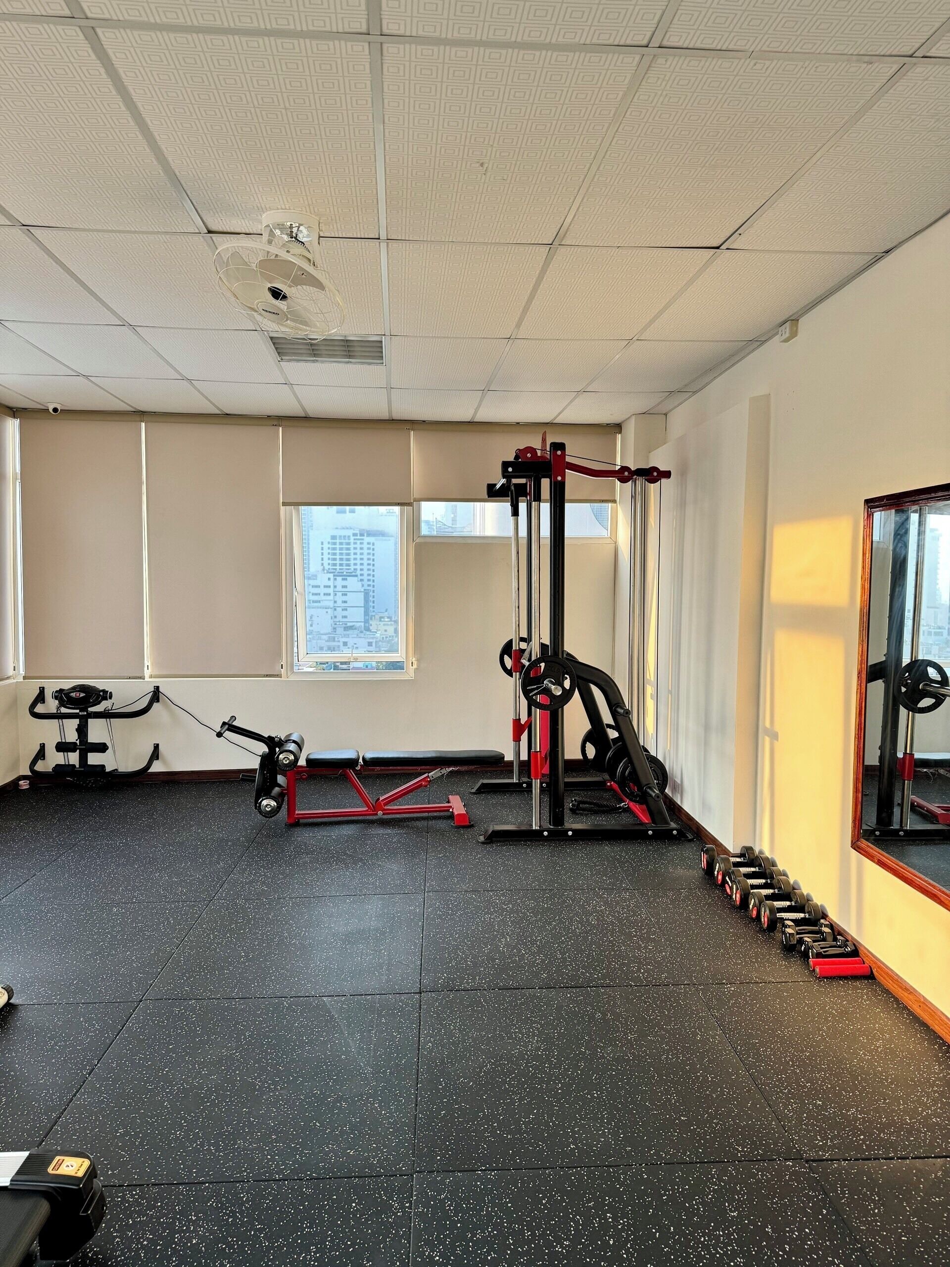 A gym with exercise equipment, a window, and a mirror.