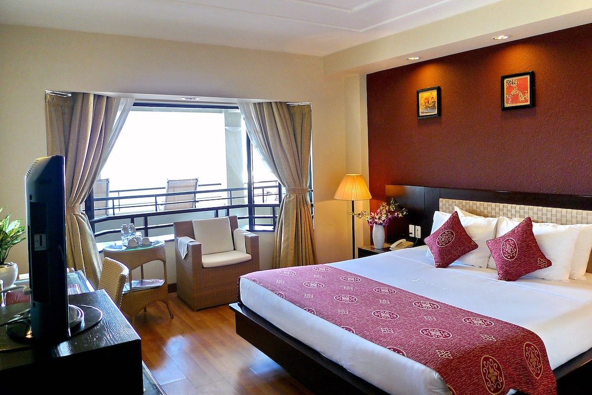 A hotel room with a large bed, a TV, a desk, and a chair.