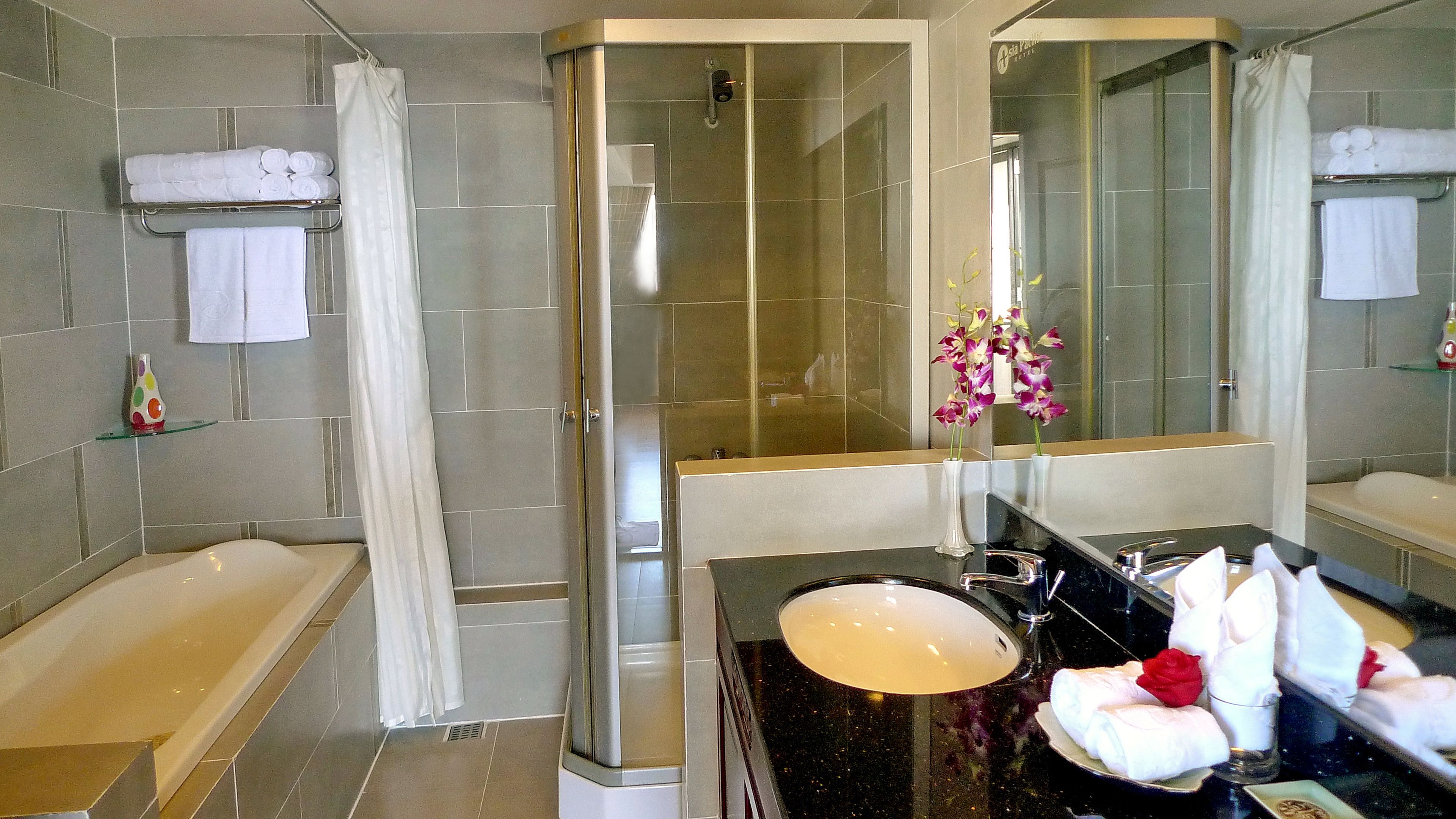 A modern bathroom with a bathtub, a shower, a sink, and a vanity mirror.