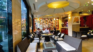 A modern interior with wicker furniture, a central glass-top table, and a bar area with shelves of bottles. - Asia Paradise Hotel (Nha Trang)