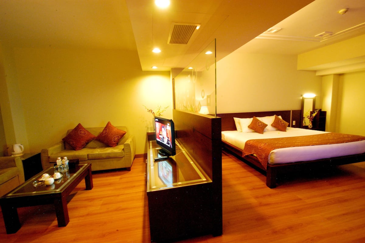 A hotel room with a bed, a sofa, a coffee table, and a TV.