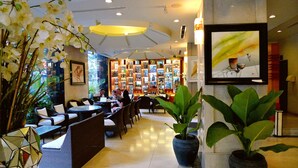 A well-lit indoor space with seating areas, a bar with shelves of bottles, and potted plants. - Asia Paradise Hotel (Nha Trang)