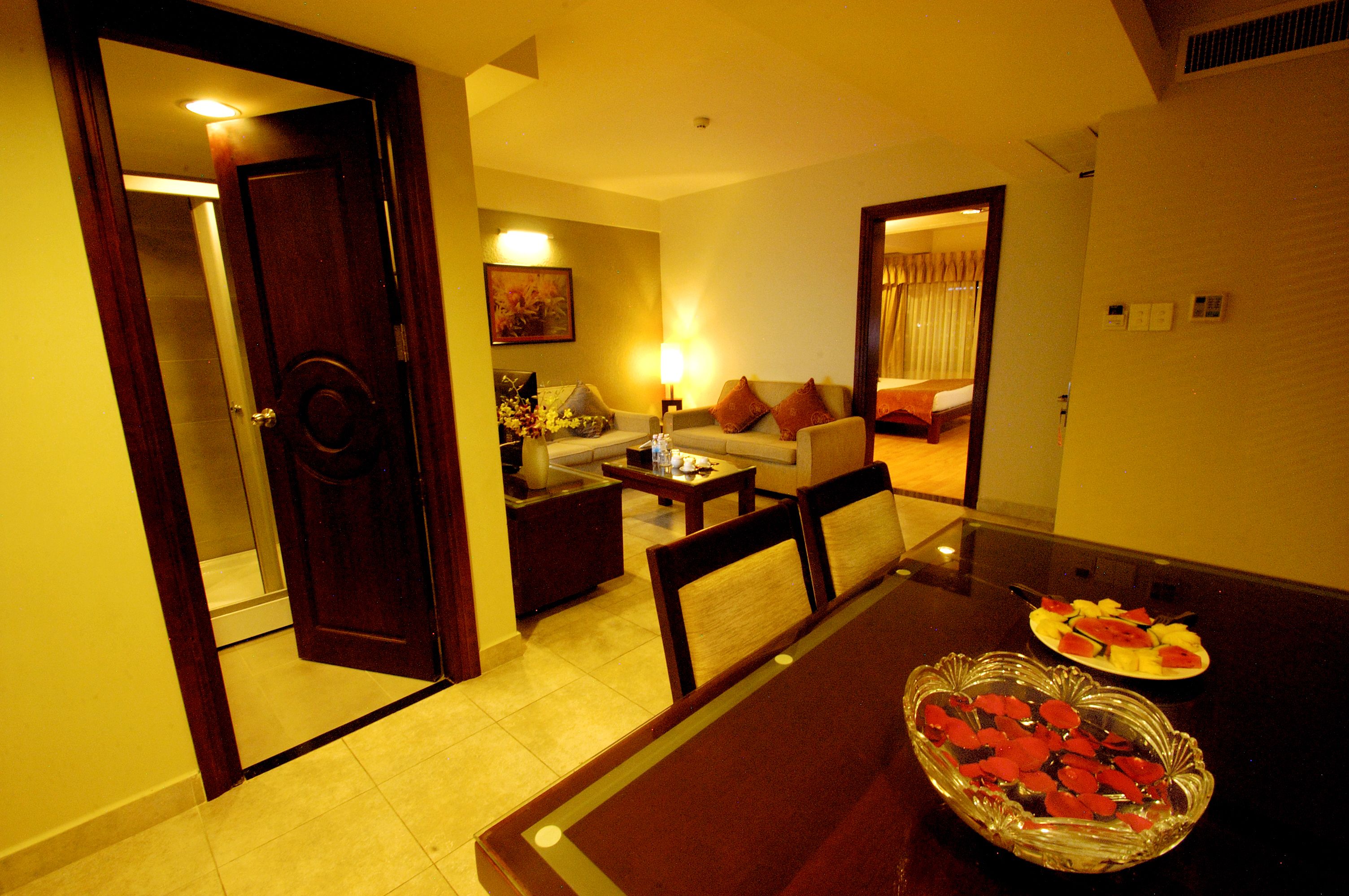 A hotel room with a dining table, chairs, a sofa, a coffee table, and a small dining table with plates of food.
