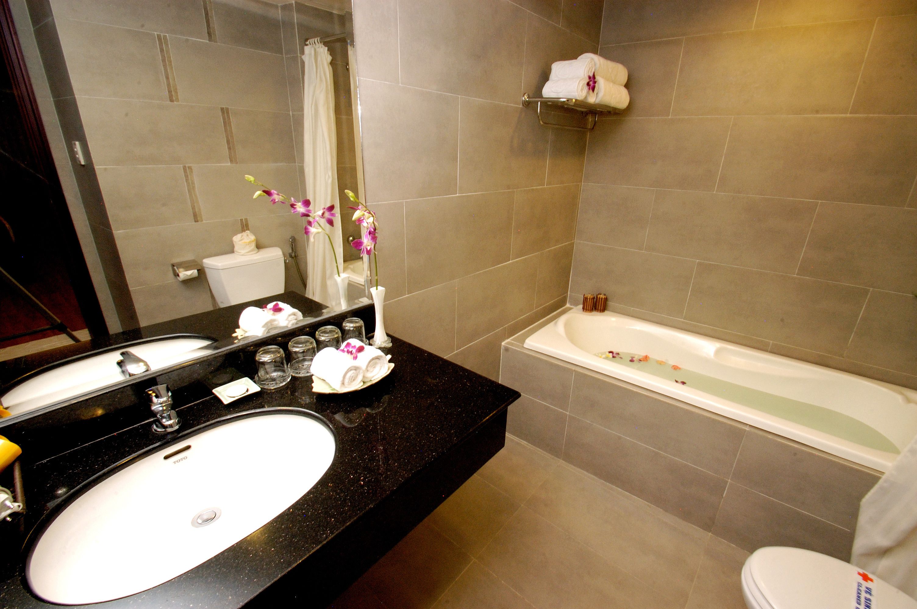 A bathroom with a black countertop, two sinks, a toilet, and a bathtub.