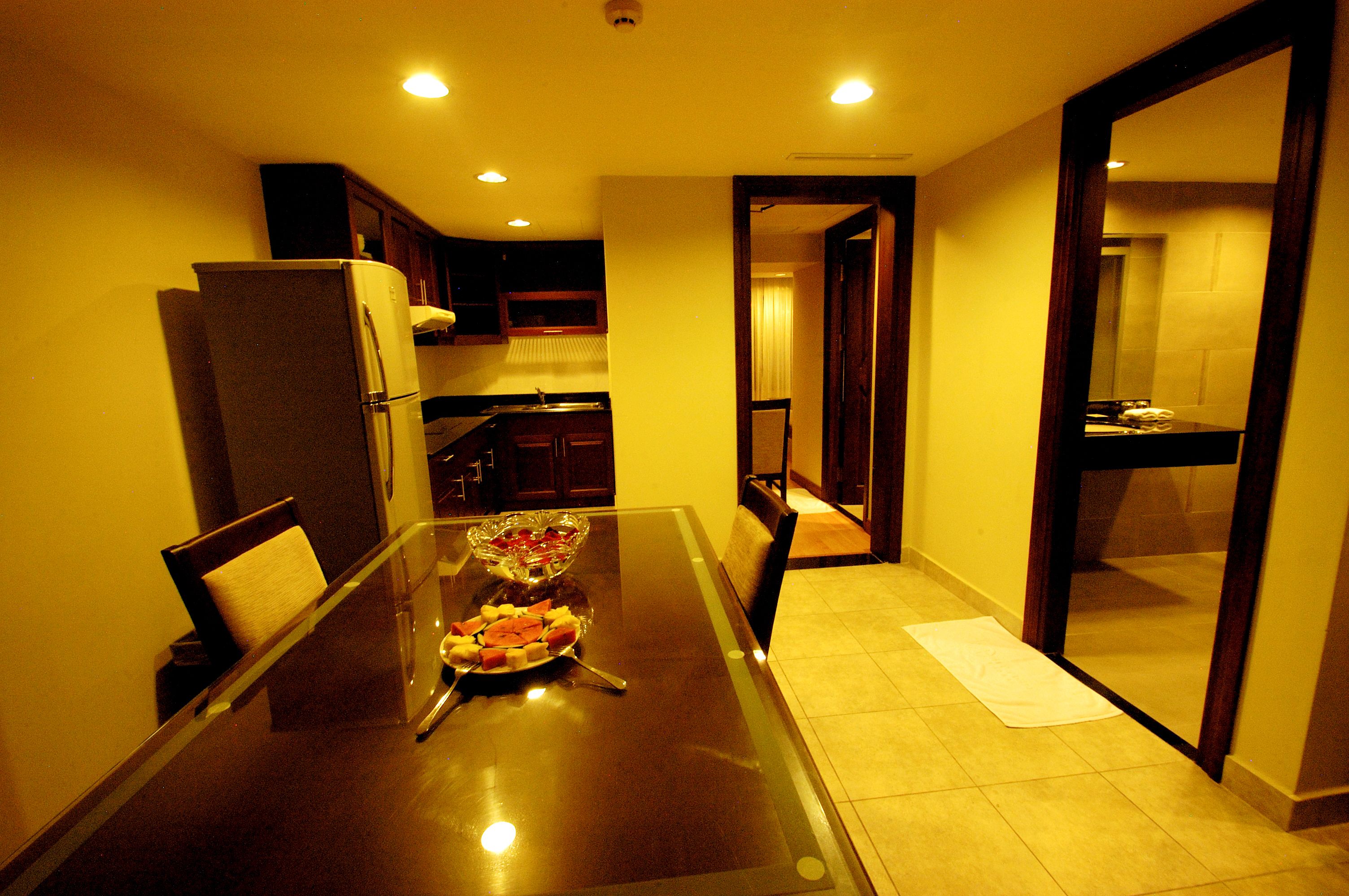 A compact kitchen with a dining table, a refrigerator, and cabinets.