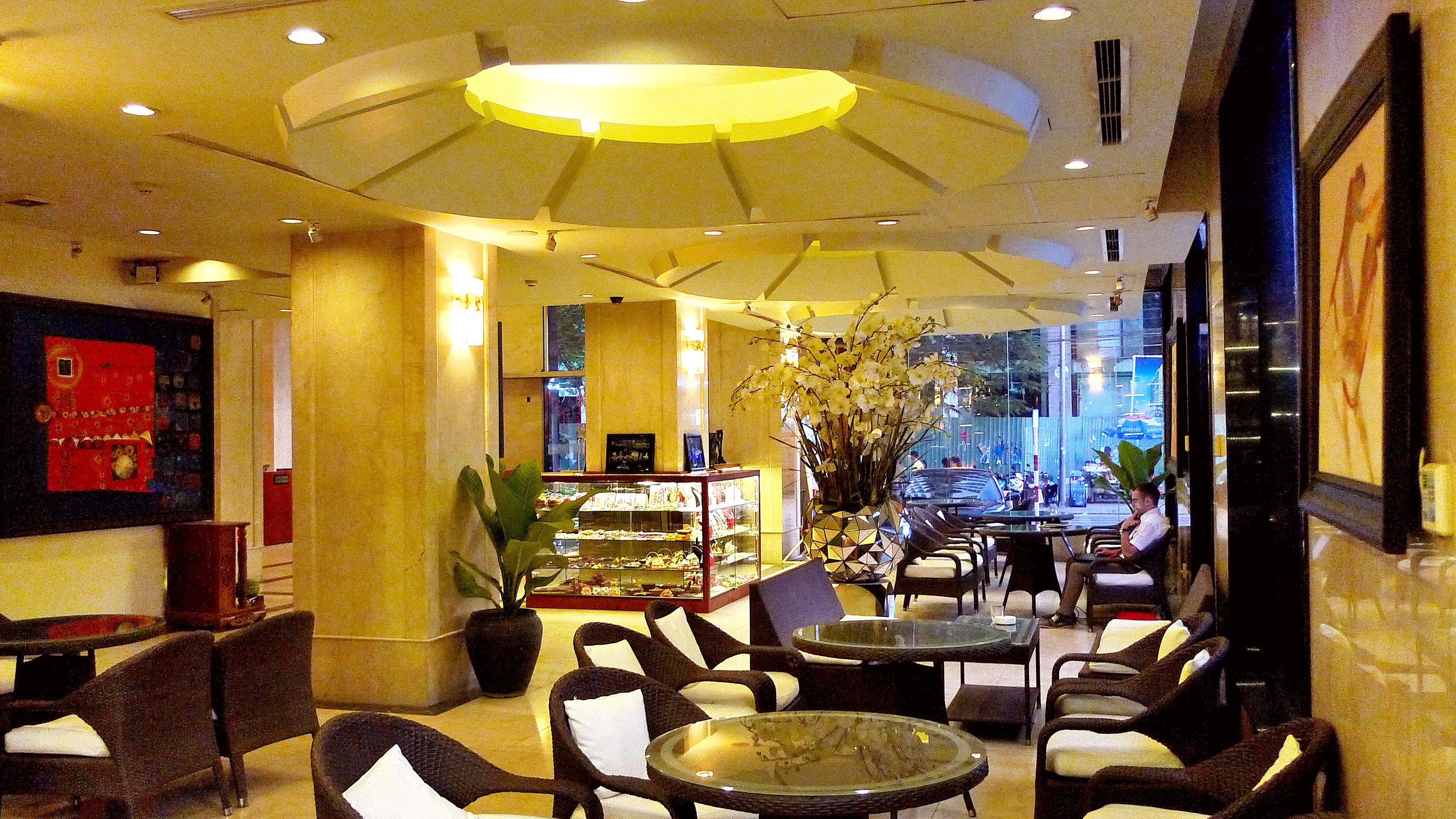 A hotel lobby with seating areas, a display case, and a large window offering a view of the street.