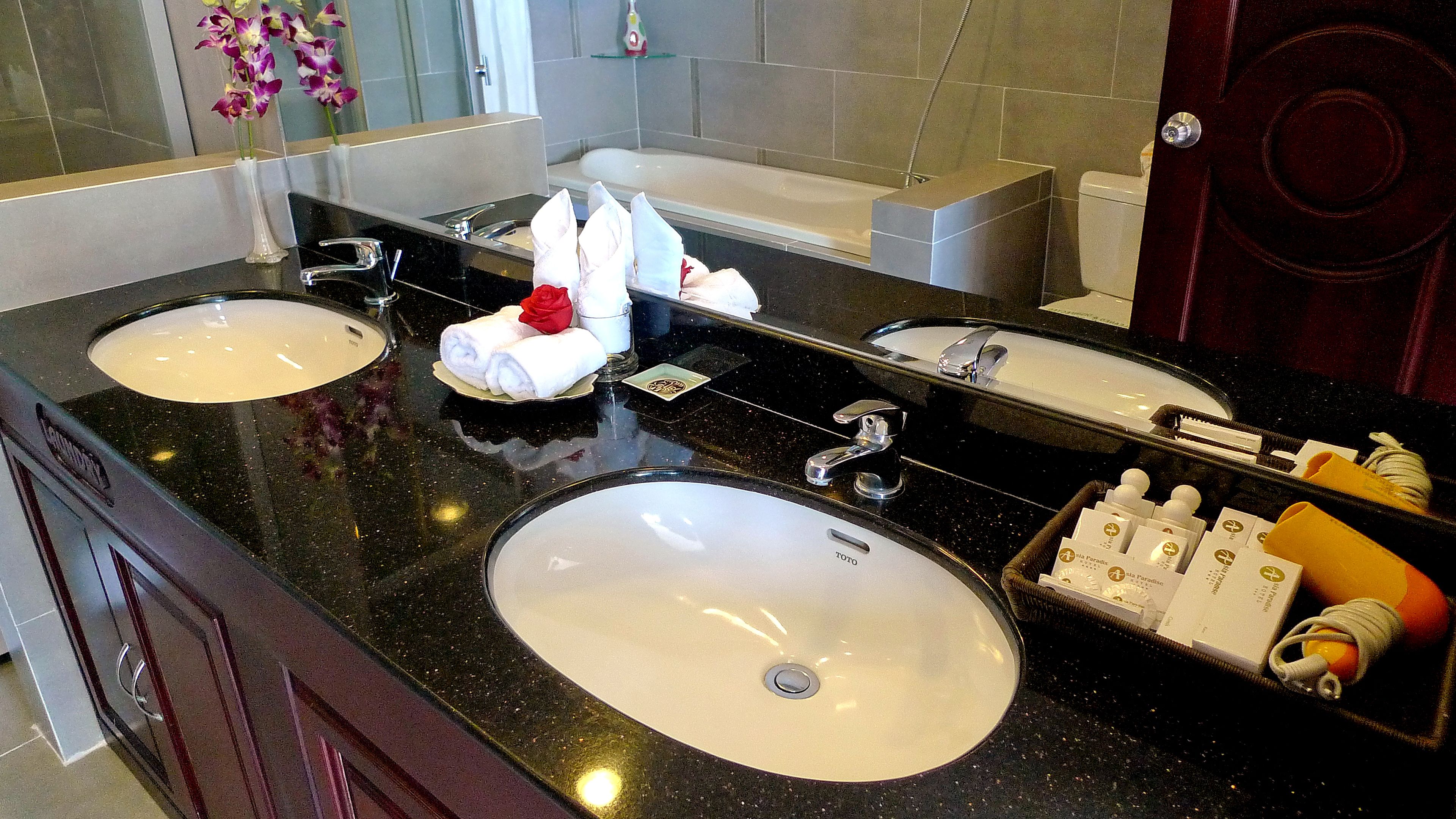 A bathroom with two sinks, a mirror, a bathtub, and toiletries.