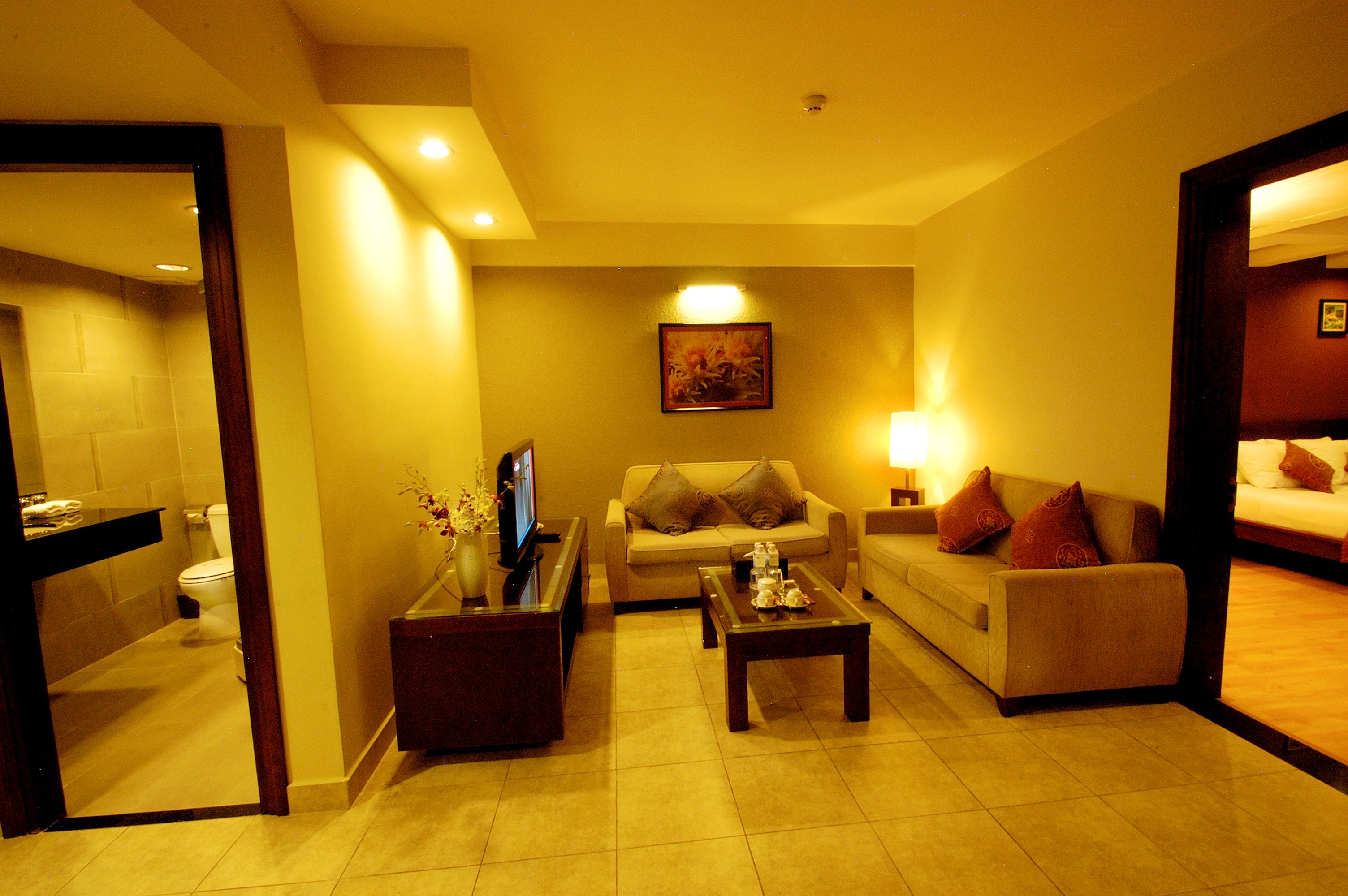 A hotel room with a sofa, a coffee table, a TV, and a painting on the wall.