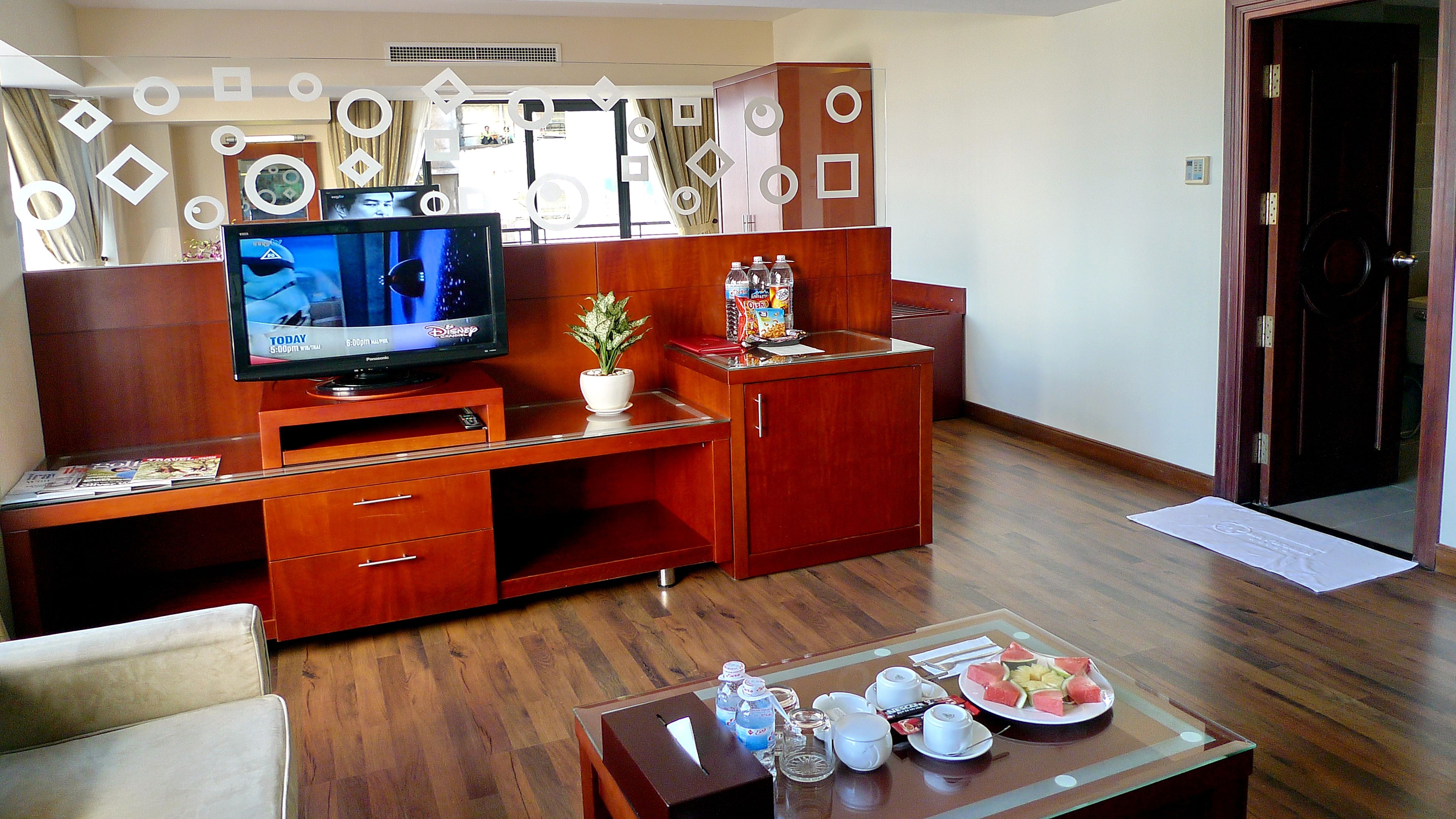 A hotel room with a wooden desk, a television, a potted plant, and a breakfast tray on the table.