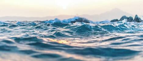 A view of the ocean with waves and distant mountains.