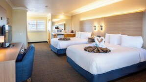A hotel room with two beds, a desk, a TV, and a kitchenette. - Cayucos Beach Inn (Cayucos)