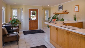 A kitchen with a wooden countertop, a chair, a door, and a window with blinds. - Cayucos Beach Inn (Cayucos)