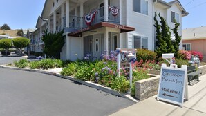 A two-story building with a balcony, a sign reading "Cayucos Beach Inn," and a welcome sign. - Cayucos Beach Inn (Cayucos)