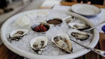 A plate of oysters on ice with a spoon and small bowls of condiments.