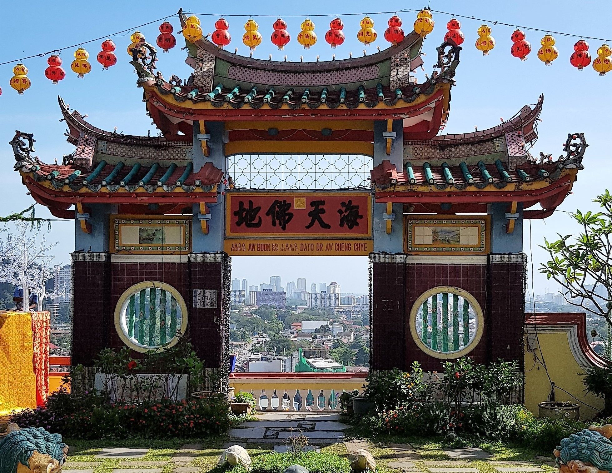 A traditional Chinese gate with ornate decorations and a clear view of the cityscape in the background.
