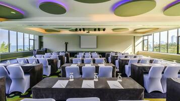 A conference room with tables, chairs, and a projector screen.
