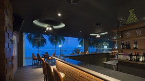 A bar area with a view of palm trees and a beach at dusk. - Mercure Penang Beach (George Town)