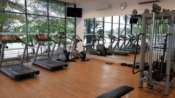 A gym with treadmills, elliptical machines, and a bench.