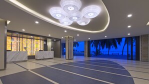 A spacious lobby with a marble reception desk, a large pillar, and a view of palm trees through the glass. - Mercure Penang Beach (George Town)