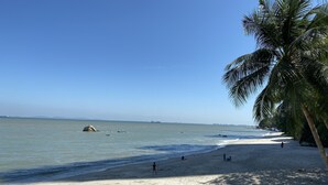 A beach with clear skies, calm waters, and a few people walking along the shore. - Mercure Penang Beach (George Town)
