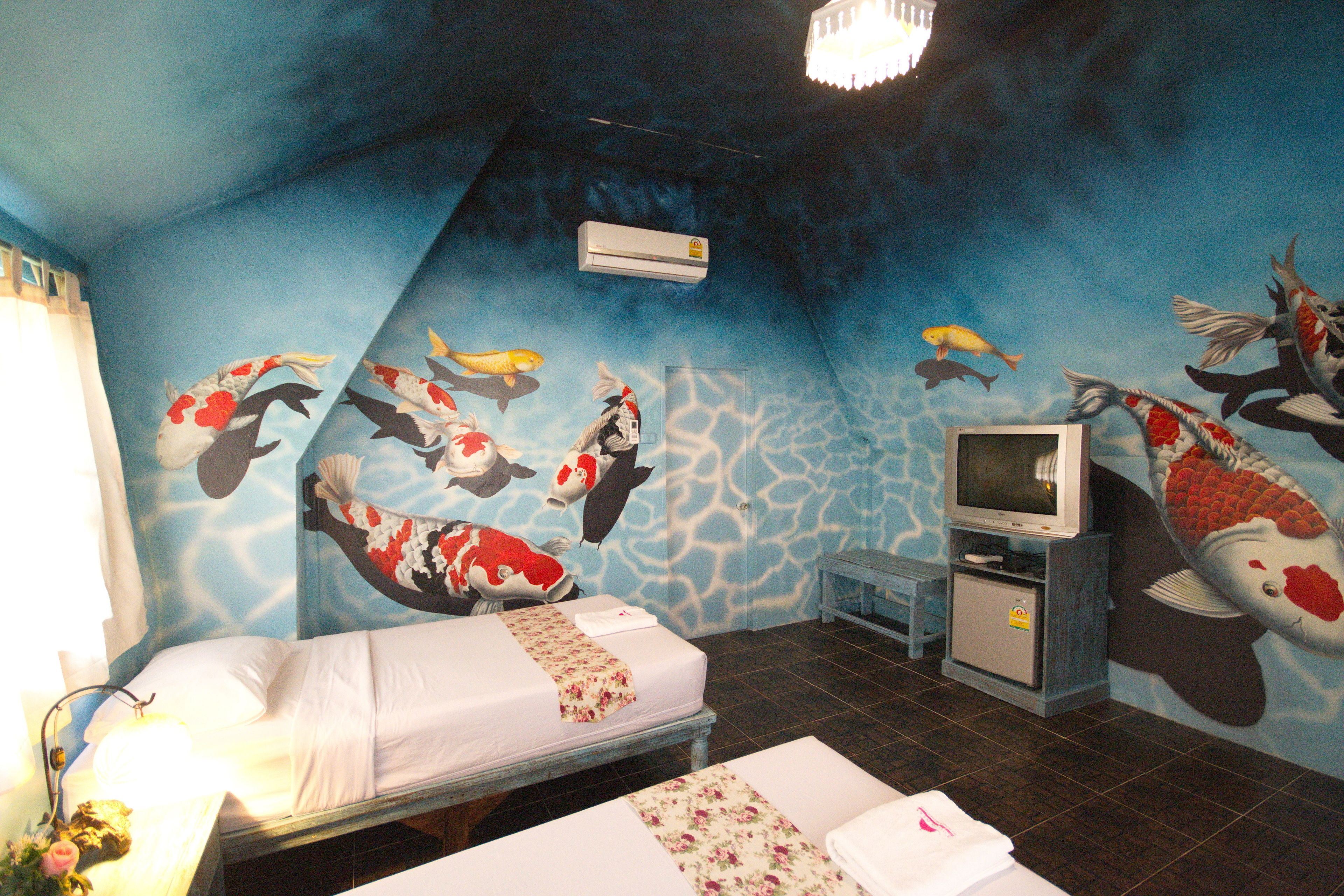 Una habitación con dos camas, televisión y un mural de peces en la pared.