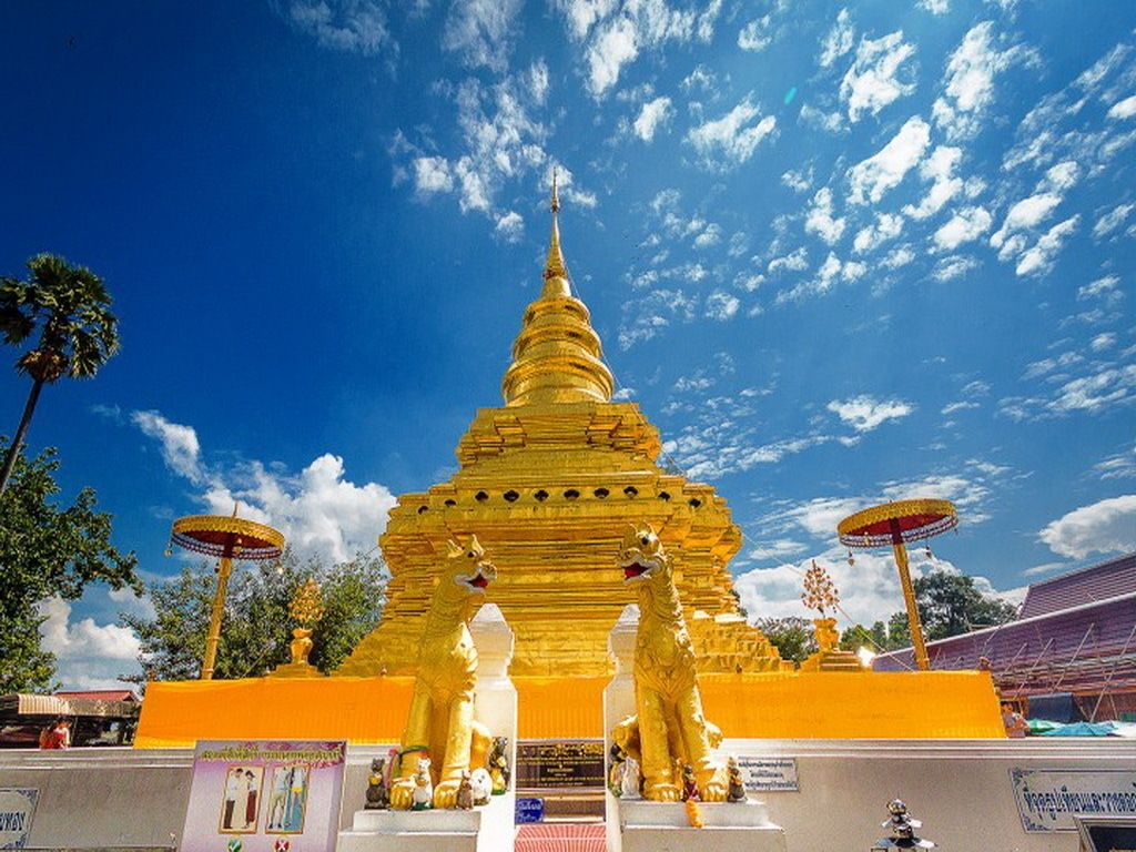 Un stupa doré, flanqué de deux statues de lions à son entrée, le tout baigné d’un ciel bleu azur.