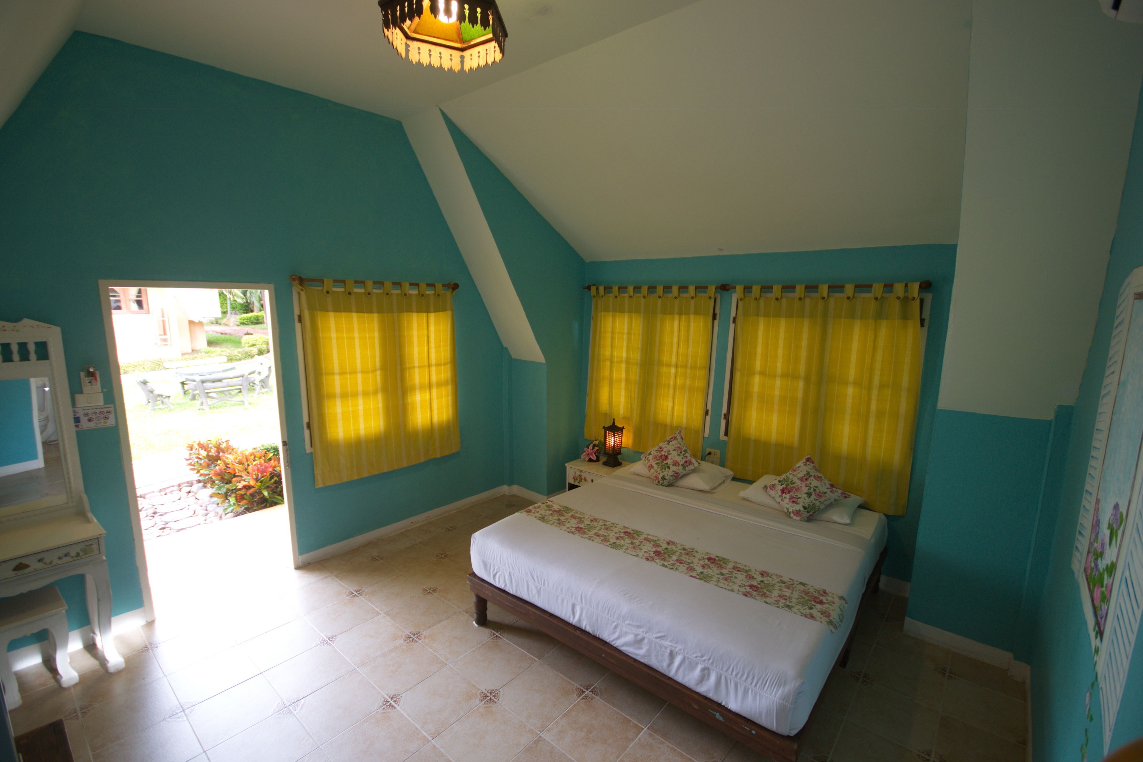Une chambre à coucher avec un lit, des rideaux, une table de chevet et une lampe.