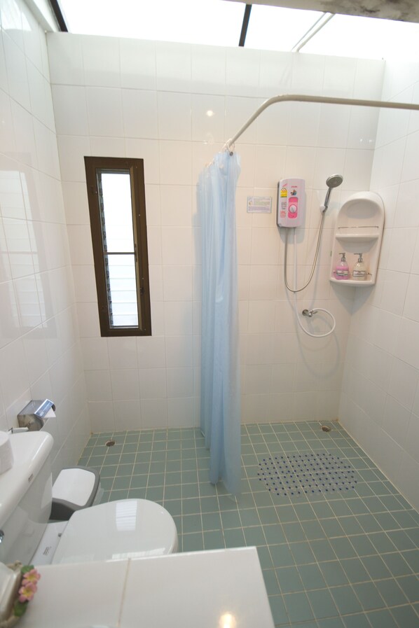 Un baño pequeño con ducha, inodoro y lavamanos.