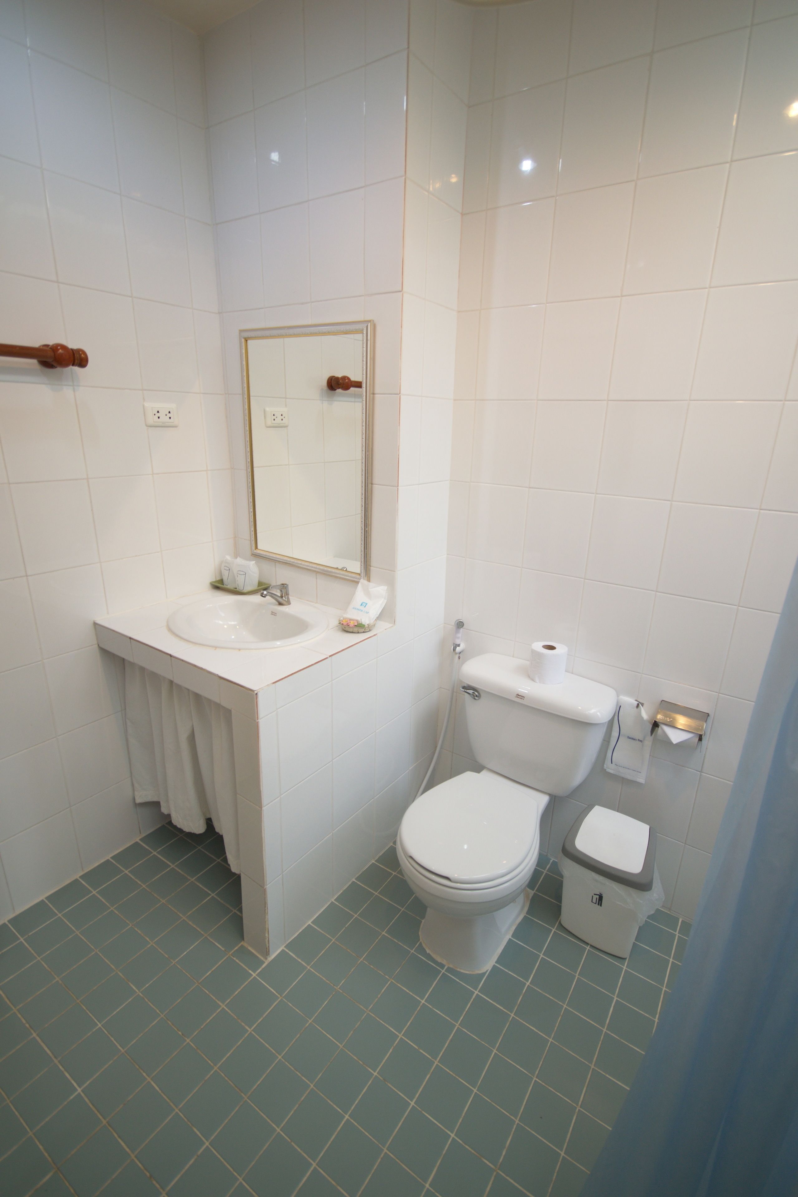A bathroom with a white sink, mirror, and toilet.