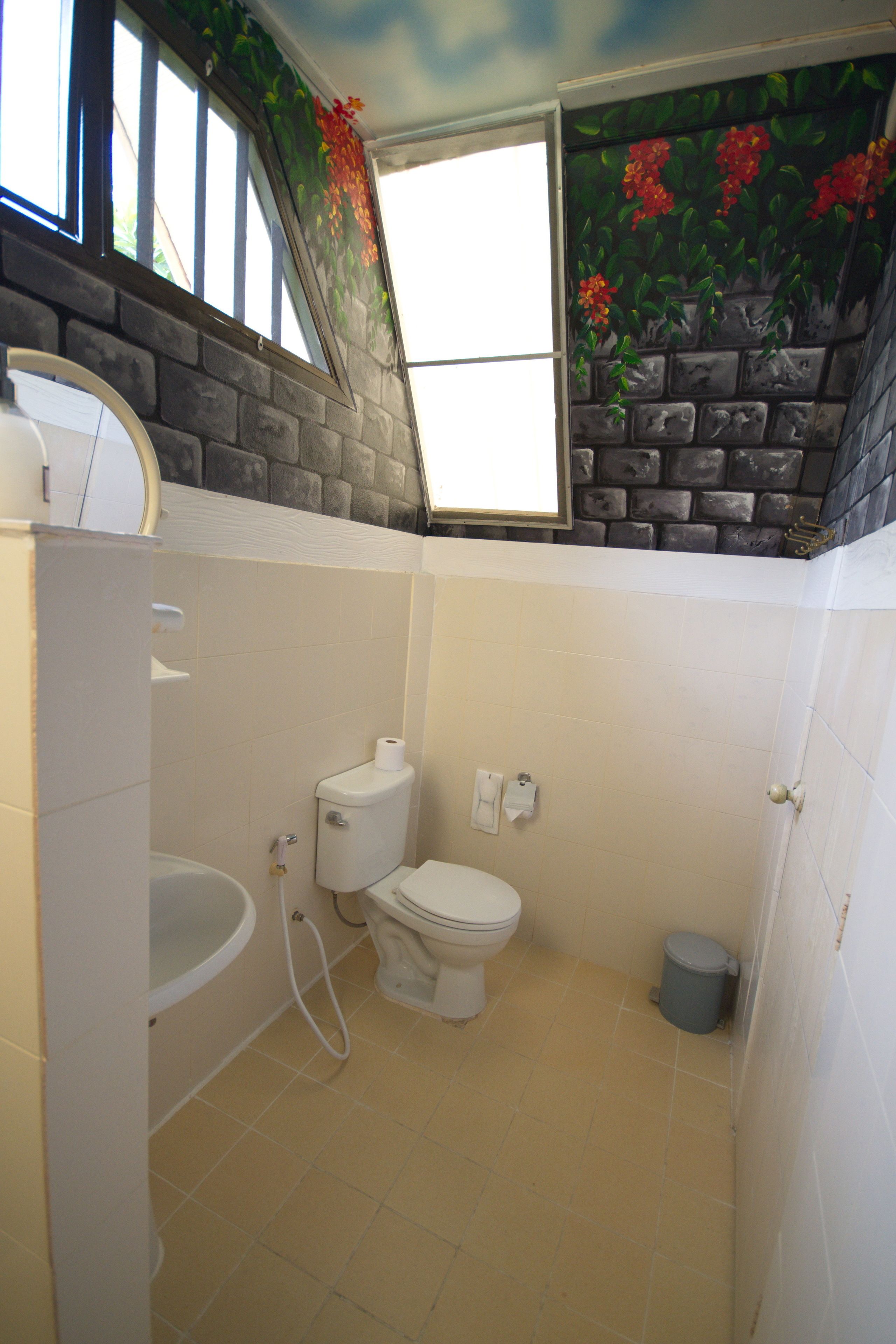 A bathroom with a toilet, sink, and shower. There is a window with a view of the outside.