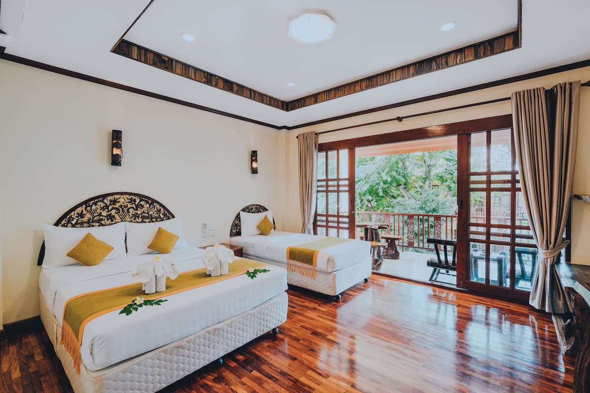 A hotel room with two beds, a balcony, and a wooden floor.