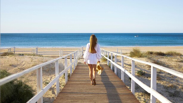 A wooden boardwalk leading to a beach with a clear view of the ocean.