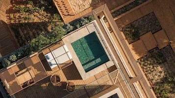 Área de piscina en la azotea con vista despejada, rodeada de terraza de madera y sillones de descanso.